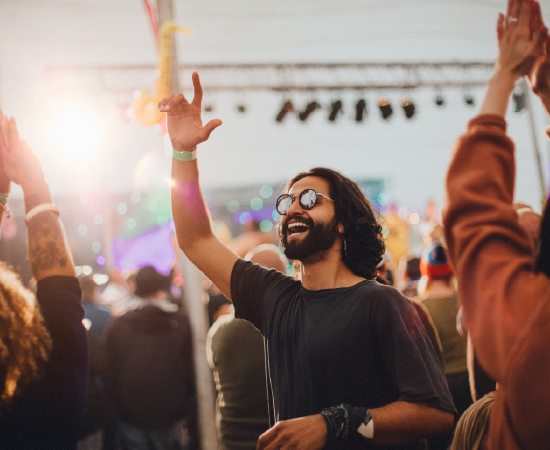 Man enjoying a music festival, surrounded by a crowd.