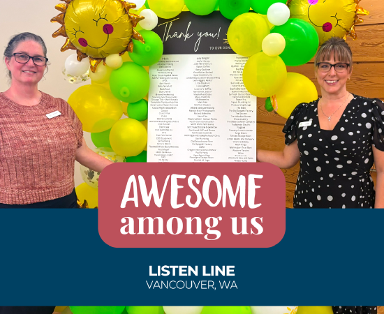 Two women smiling at a celebration with balloons and a thank you board.