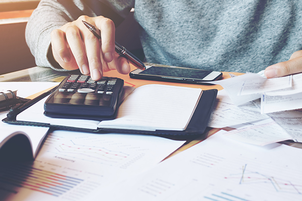 man reviewing statements and receipts with hand on calculator