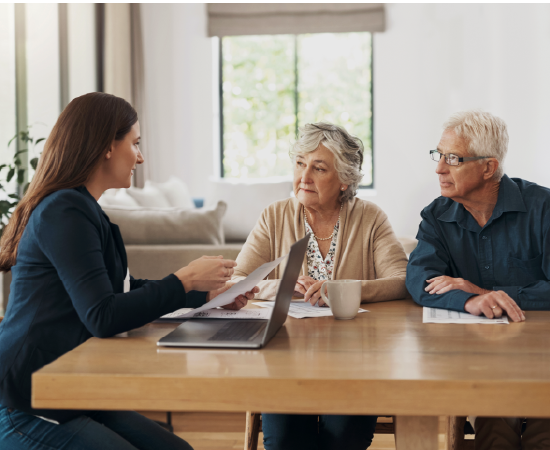 Advisor meeting with senior couple at home table.