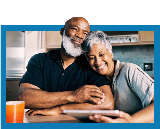 senior couple sitting at table with coffee and tablet