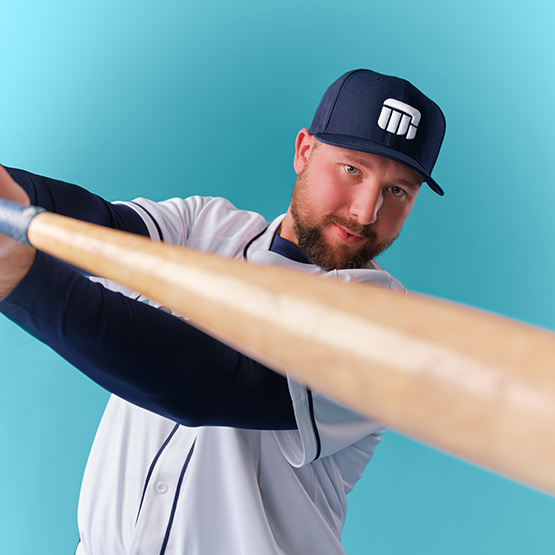 Cal Raleigh swinging a baseball bat with a light blue background
