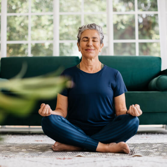 mature woman meditating in living room