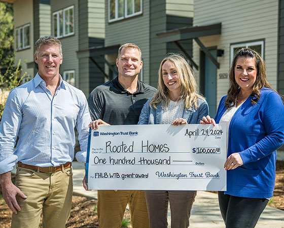 Employees present check to Rooted Homes