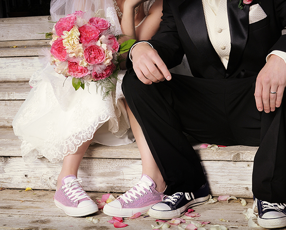 Bride and groom sitting on steps with sneakers on.