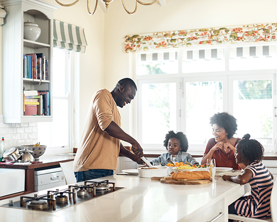 Black family of 4 having breakfast in a bright kitchen.