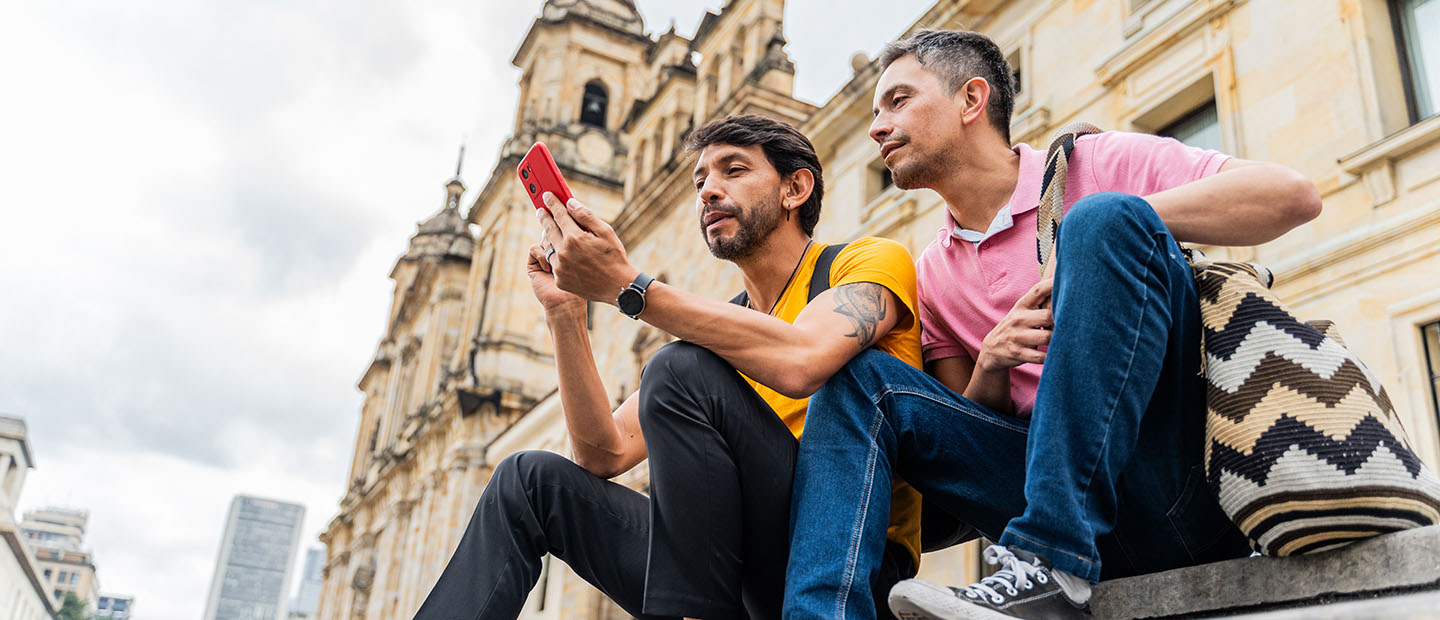 two men sitting on steps looking at cell phone gps