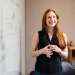 smiling woman in front of whiteboard