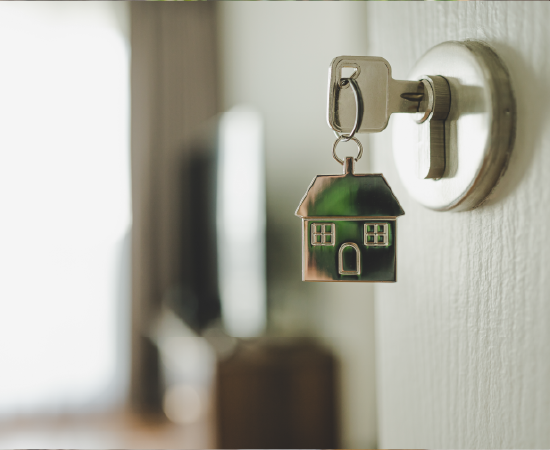 House-shaped keychain hanging from door lock.