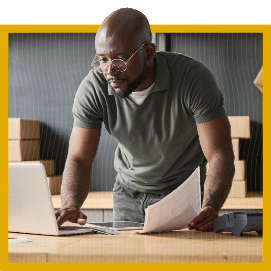 man holding paperwork and looking at laptop