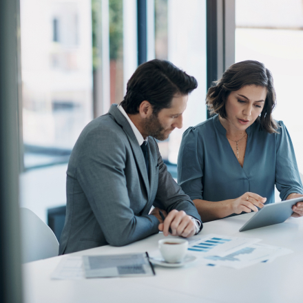 two businesspeople looking at tablet and documents 