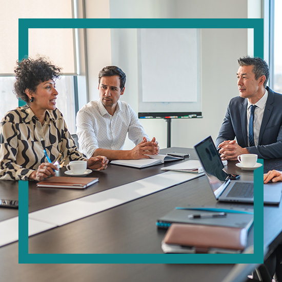 Three people at a conference table discussing business.